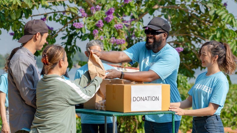 african,man,volunteer,give,some,food,in,paper,bag,to